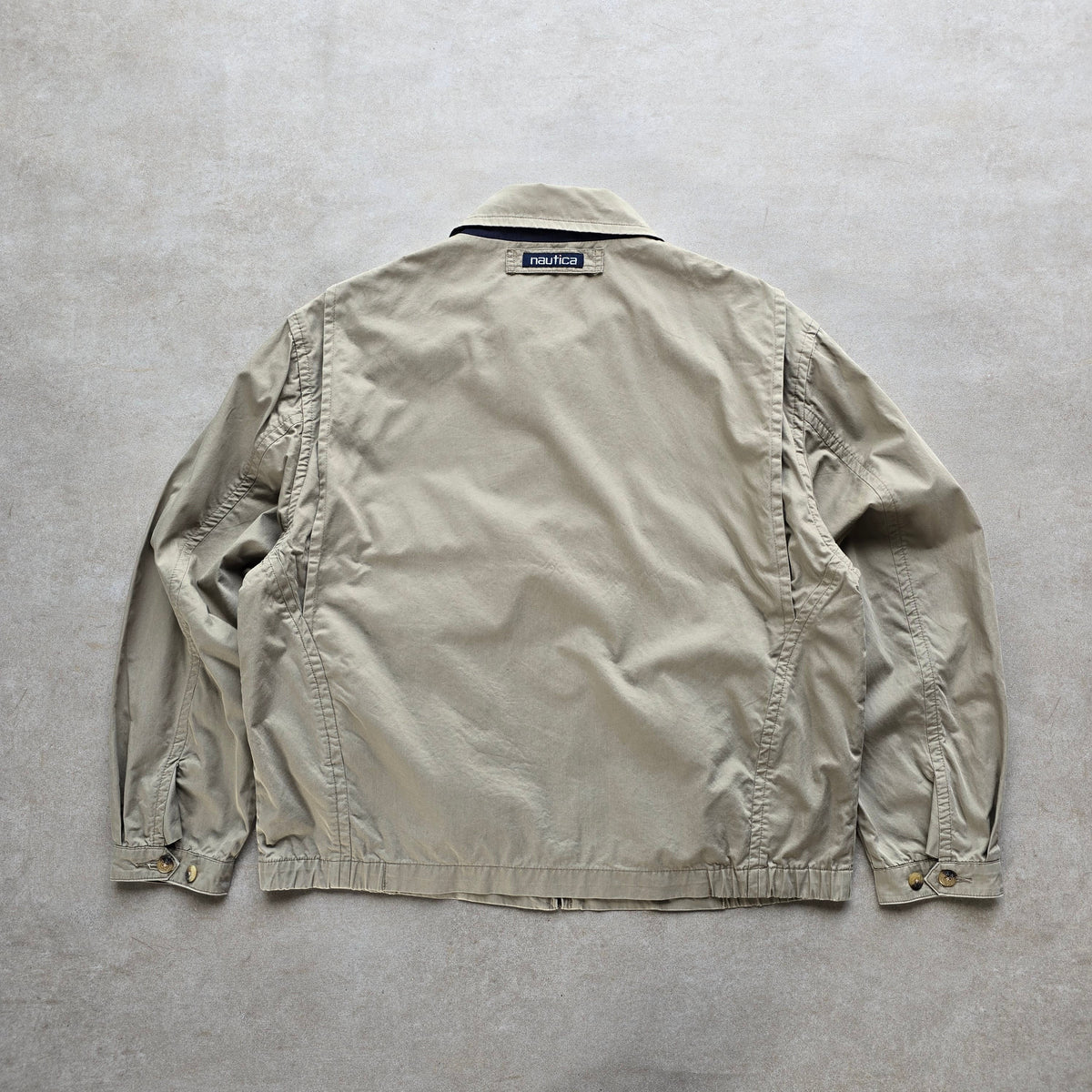 Back view of a vintage 90s DEEP VINTAGE Nautica Harrington jacket in beige with a classic collar and logo patch.