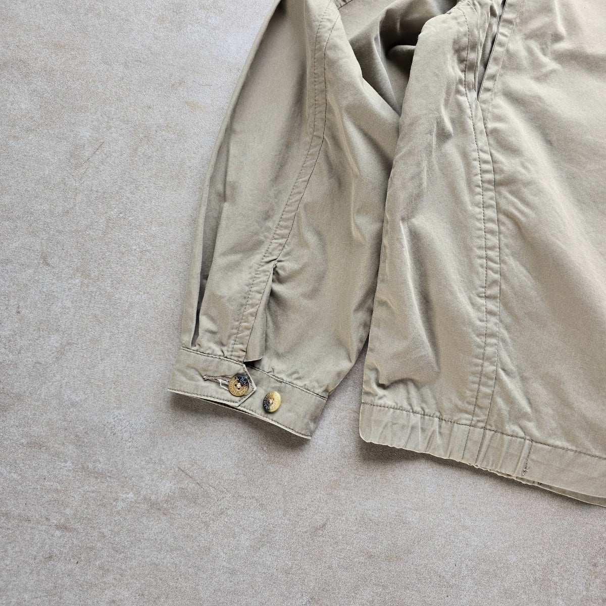 DEEP VINTAGE beige 90s Nautica Harrington jacket sleeve detail with buttoned cuff on a neutral background